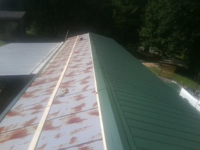 Old rusted panels beside newly installed green metal roofing — Wind Damage Roof Repair by Roofing Brothers in El Cajon