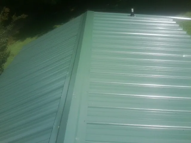 New green metal panels meeting at the ridge of a roof — Flat Roof Repair work by our crew in El Cajon