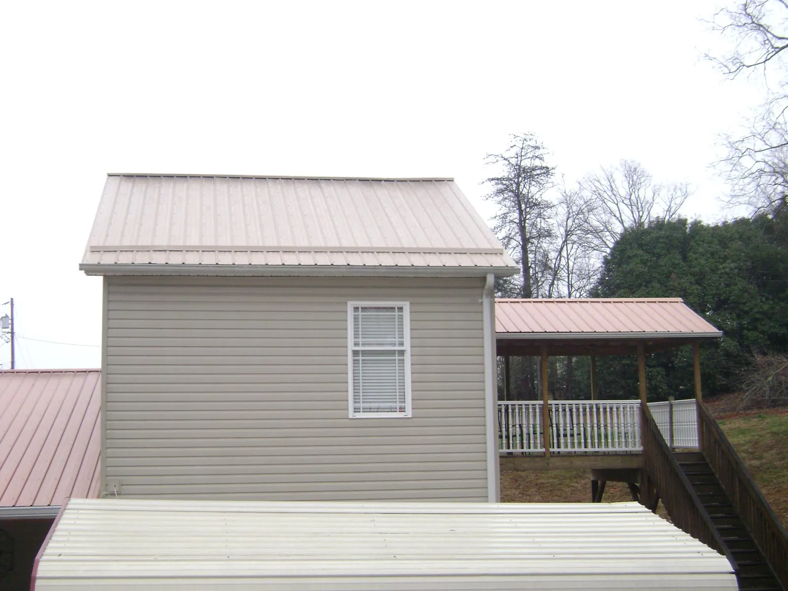 Tan metal roofs on a two story addition and attached porch, from a Roof Replacement job in El Cajon