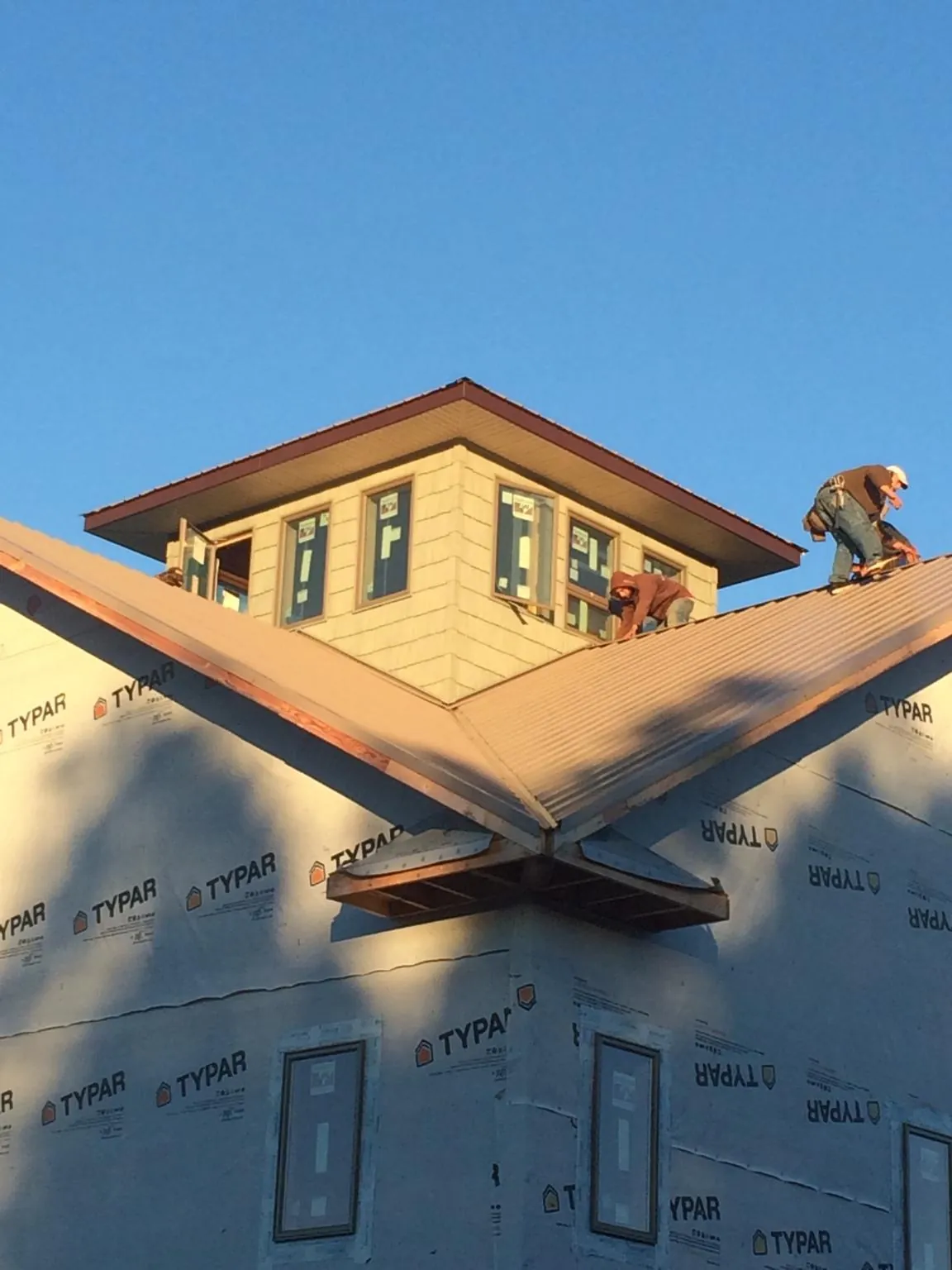 Roofers working around a rooftop cupola on a new metal roof at sunset — Roof Waterproofing in El Cajon by Roofing Brothers